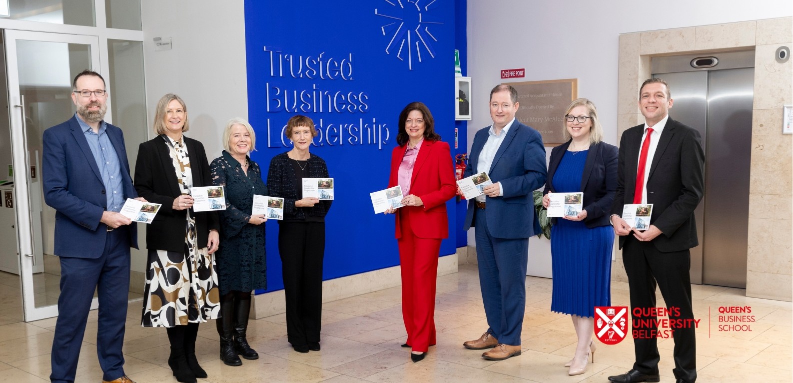 A group of well dressed people holding brochures